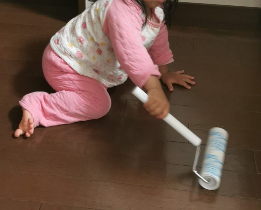 床にコロコロをかけて掃除する子供