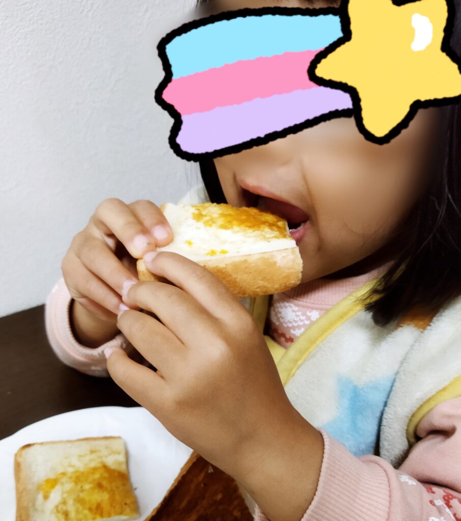 くり抜き卵トーストを手で持って食べる娘