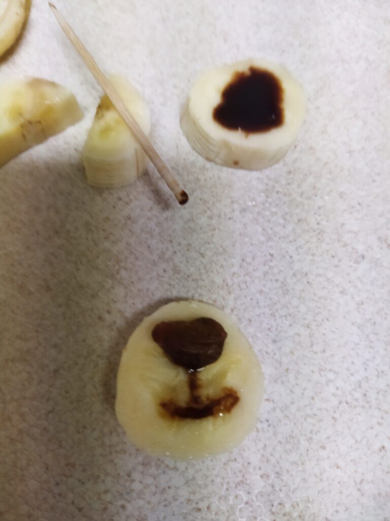 輪切りのバナナにチョコソースで鼻の下の線と口を描いた様子
