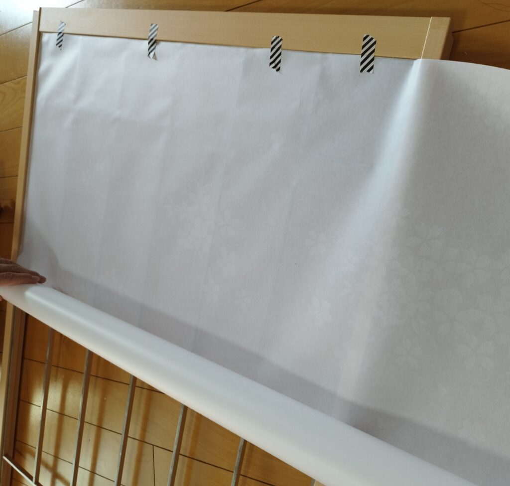 プラスチック障子紙をマスキングテープで固定して少しづつ貼っていく様子