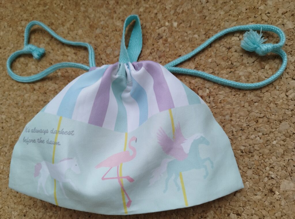 横長タイプの給食袋（メリーゴーラウンド）の口を閉じた様子